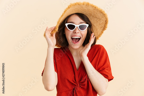 Portrait of joyous amazed vacation woman wearing straw hat and fashionable sunglasses rejoicing at camera