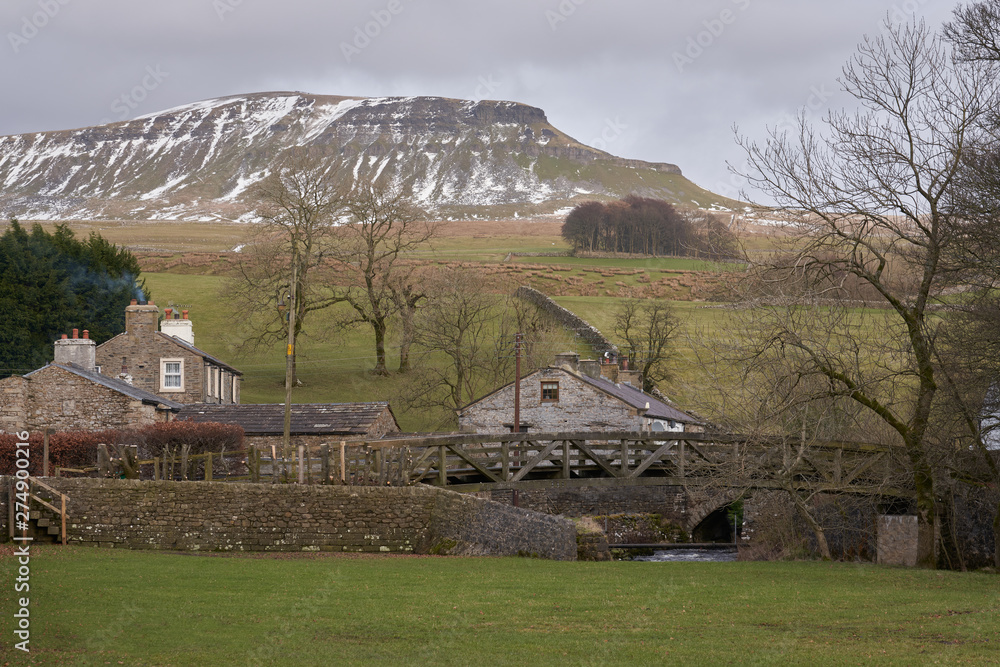Views of Pen-y-ghent with winter snow with Horton in Ribblesdale in the foreground.