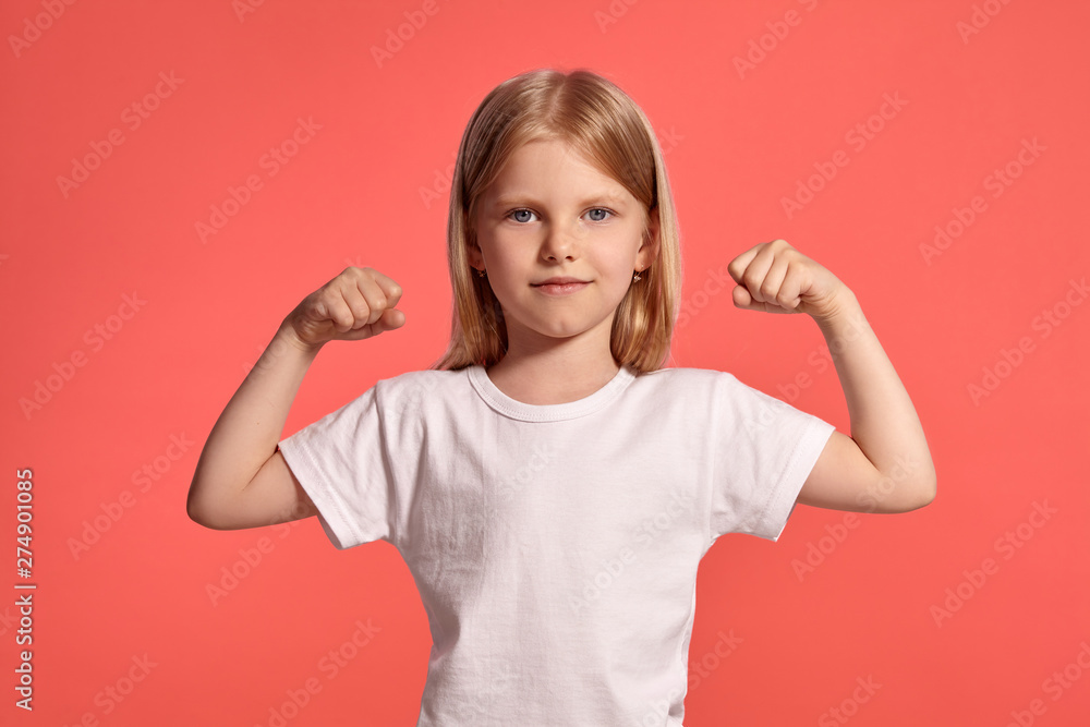 Close-up studio shot of a nice blonde little girl in a white t-shirt posing against a pink background. Close-up studio shot of a nice blonde little girl in a white t-shirt posing against a pink background.