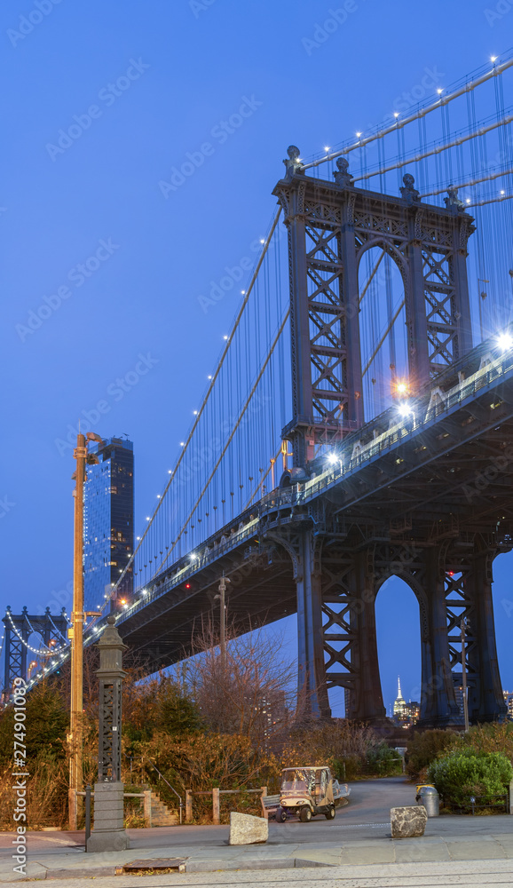 Fototapeta premium Night view of the Empire State Building through the pylons of Manhattan Bridge. View from Washington Street in Dumbo
