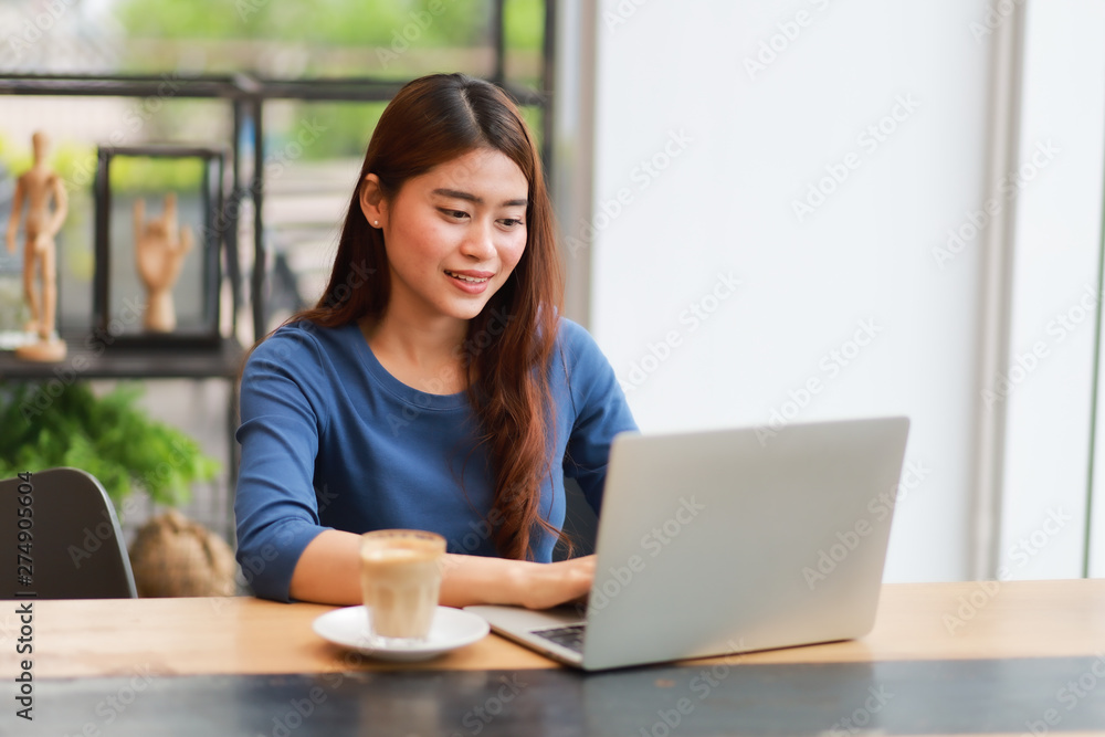 Asian woman drinking coffee and working with laptop computer in cafe Asian woman drinking coffee and working with laptop computer in cafe