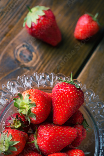 ripe strawberry in glass bowl at wooden table. close up. flat lay photo