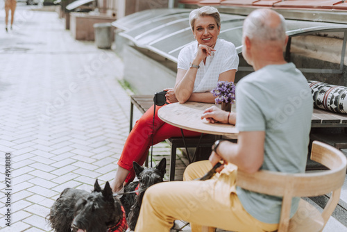Canvas Print Adult couple with dogs sitting in cafe outdoors