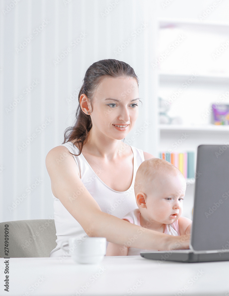 nice young working mother sitting at home and doing freelance work while holding her daughter nice young working mother sitting at home and doing freelance work while holding her daughter