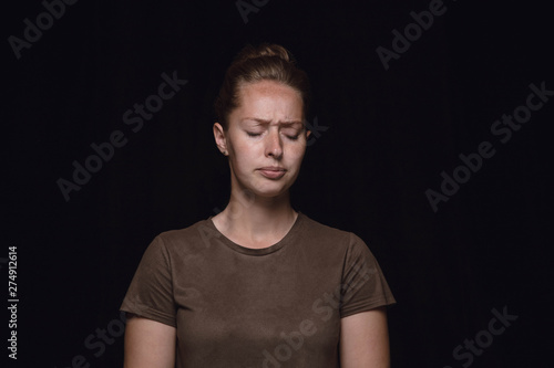 Close up portrait of young woman isolated on black studio background. Photoshot of real emotions of female model. Mourning, mental suffering. Facial expression, human nature and emotions concept.