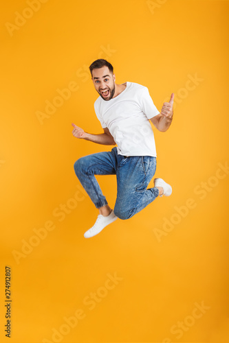 Full length photo of handsome caucasian man having beard jumping and showing thumbs up
