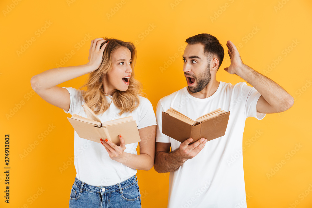 Image of impressed couple man and woman expressing wonder while reading books together Image of impressed couple man and woman expressing wonder while reading books together