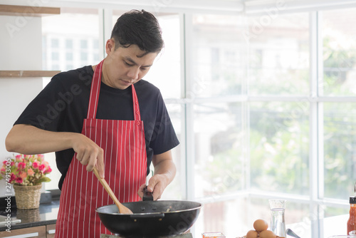 Concentrated young man cooking healthy food in modern kitchen room