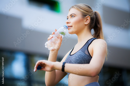 Fitness women. Woman drinking water from bottle in nature