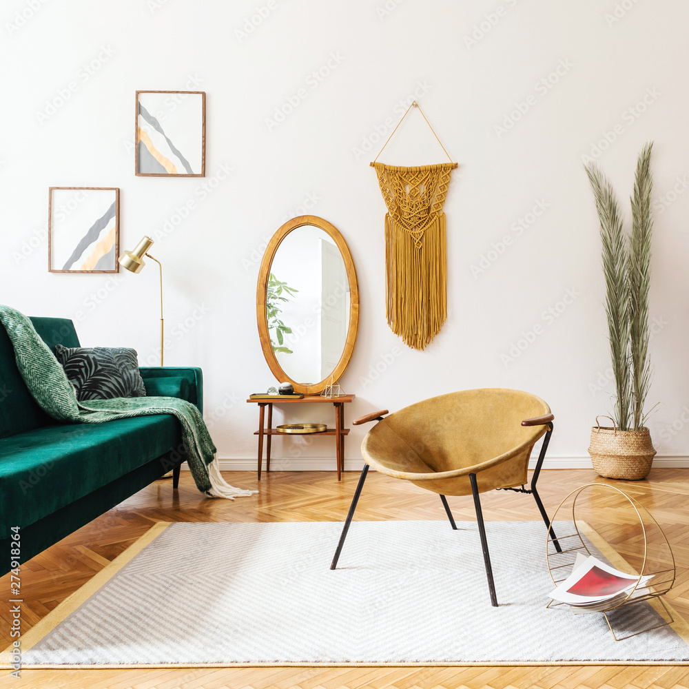Fotka „Stylish and elegant interior of living room with design gold  armchair, velvet sofa, lamp, poster frames. dressing table with mirror,  plants, palm leaves, yellow macrame and accessories. Home decor. “ ze