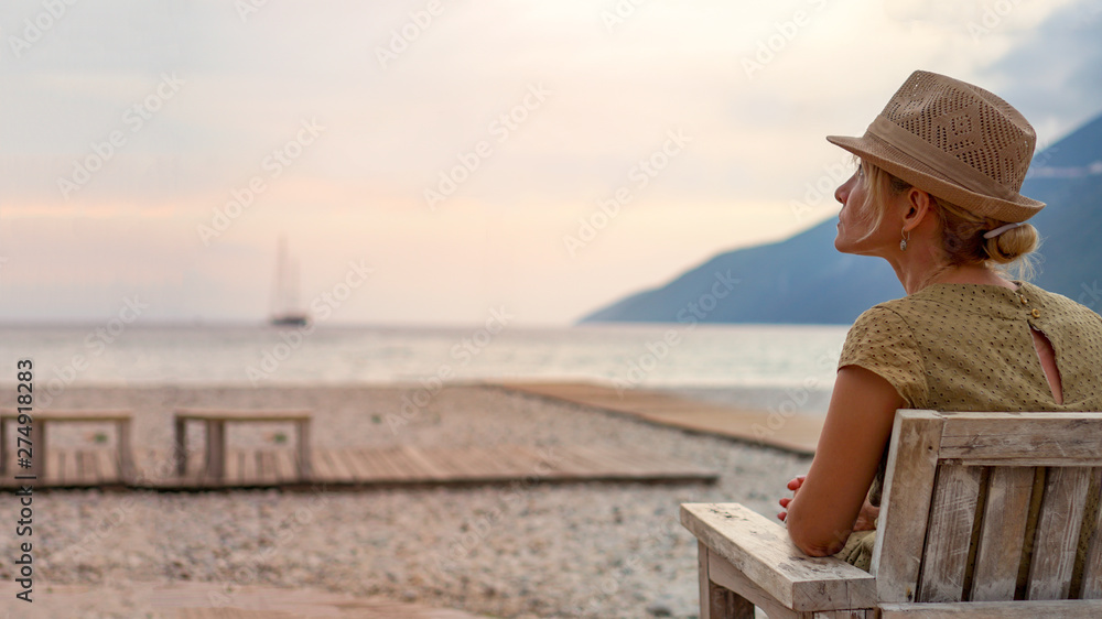 The woman sits on the beach in the sunset