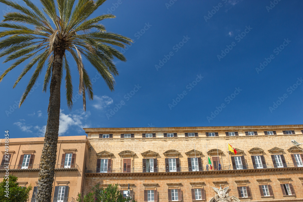 Front side of historic royal palace in Palermo Sicily, royal palace and residence of old kings with beautiful palm