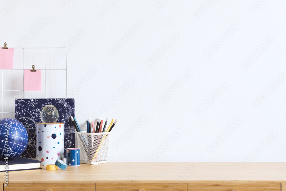 Cosmic and stylish home office interior with wooden desk, cool office  accessories, tapes, supplies, notebooks, memo sticks, pencils. Modern home  decor. Minimalistic concept. Template. Copy spce. Stock Photo