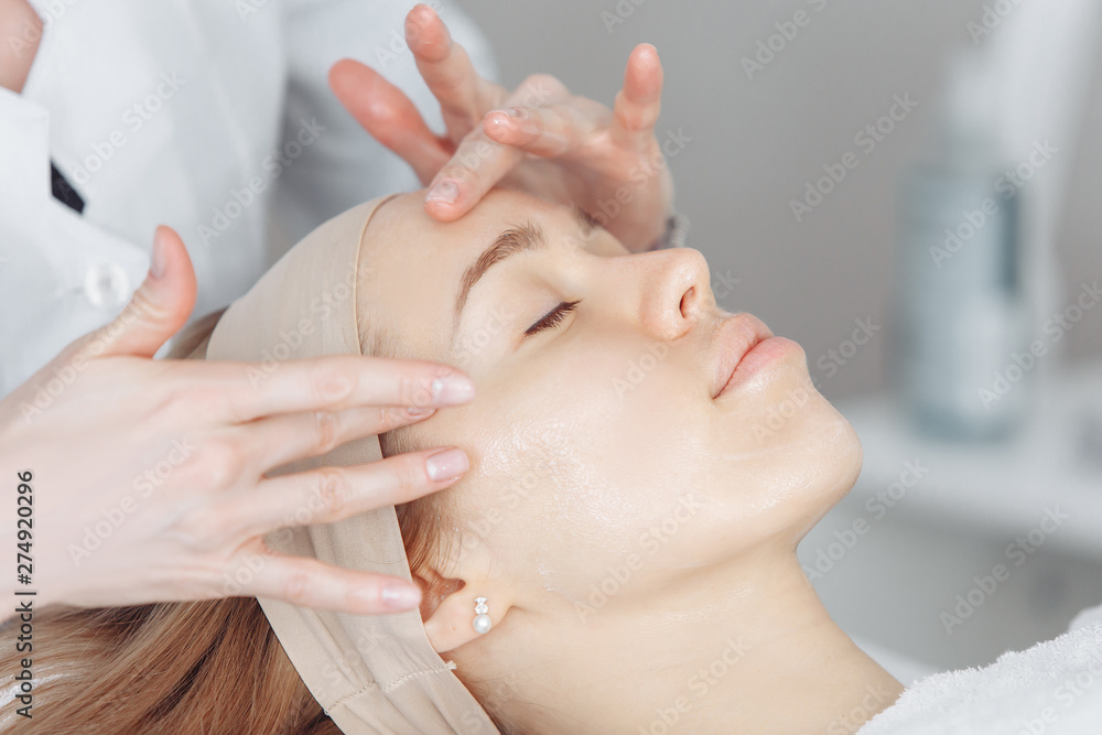Unknown masseuse beautician doing a face massage to her client a beautiful young woman. Skin care concept Unknown masseuse beautician doing a face massage to her client a beautiful young woman. Skin care concept