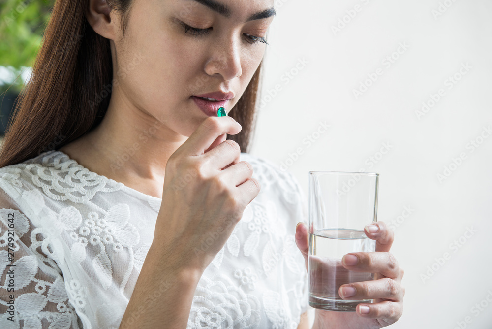 Young woman taking medicine pill after doctor order