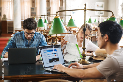 Wallpaper Mural Smart cheerful teenagers studying at the library together Torontodigital.ca