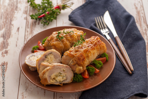 Stuffed chicken roll s vegetable garnish and herbs.