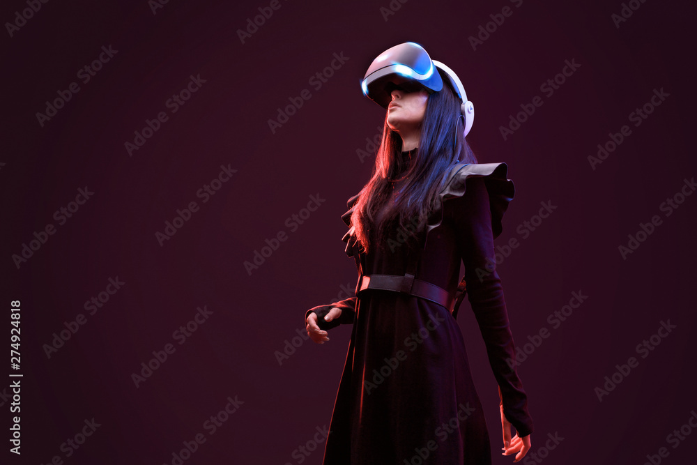 Beautiful woman in futuristic dress over dark background. Girl in glasses of virtual reality. Augmented reality, science, future technology, robots and people concept. VR.