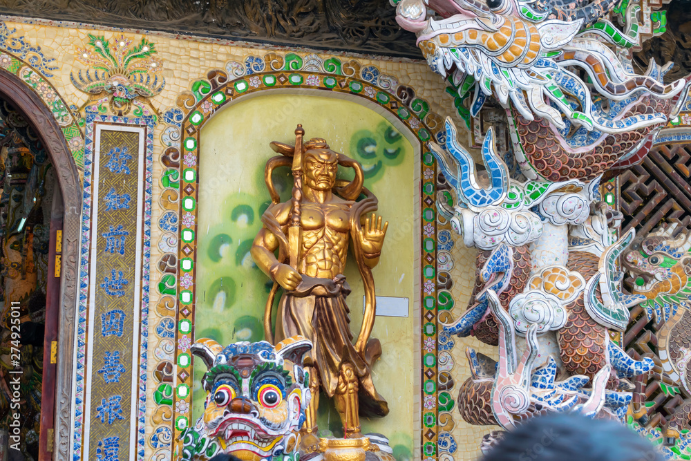 Golden statue of warrior in colorful temple in Vietnam