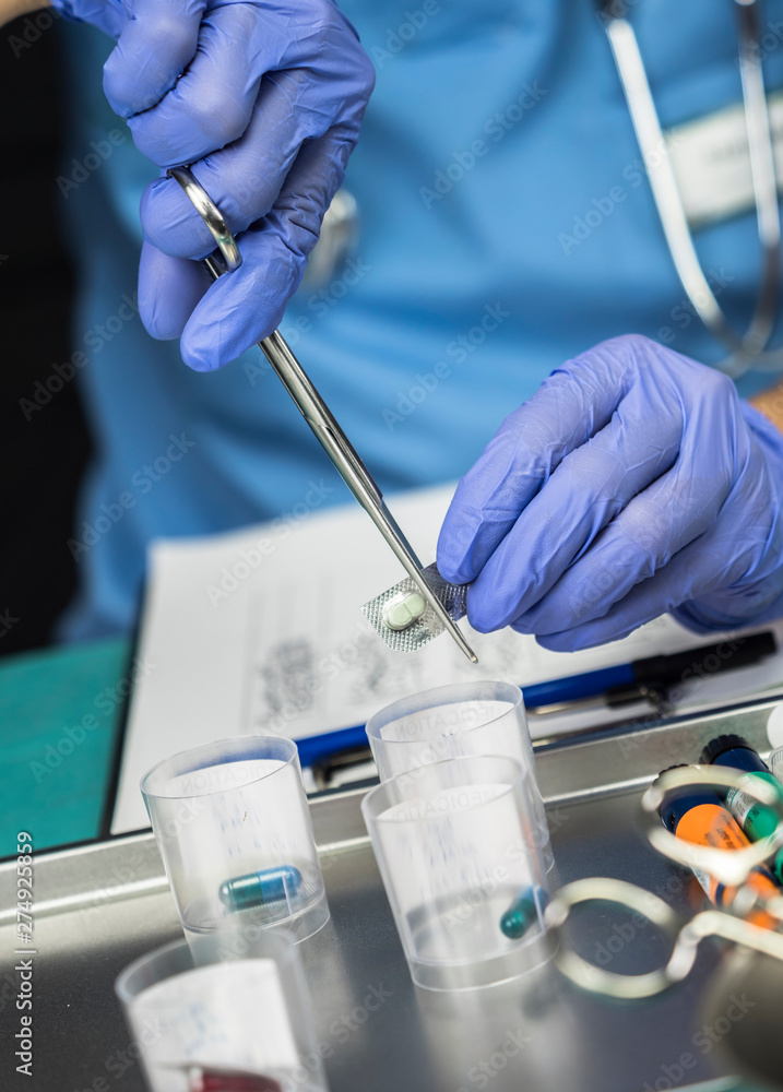 Nurse cuts dose pills for patient in a hospital, conceptual image Nurse cuts dose pills for patient in a hospital, conceptual image