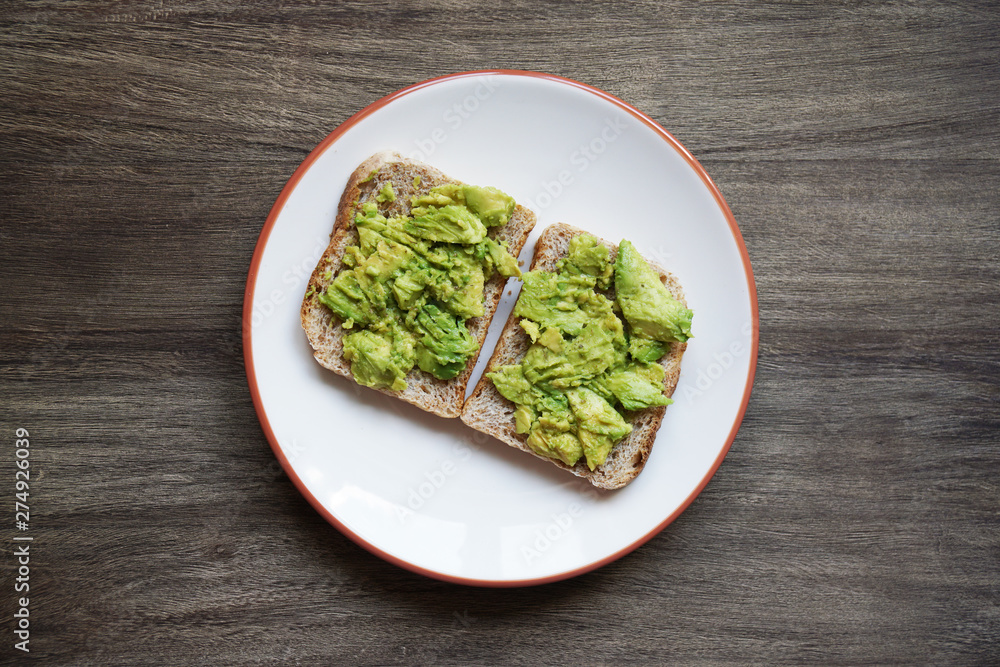 top view of two slices of homemade avocado toast on a plate on rustic wooden table - hipster food trend top view of two slices of homemade avocado toast on a plate on rustic wooden table - hipster food trend