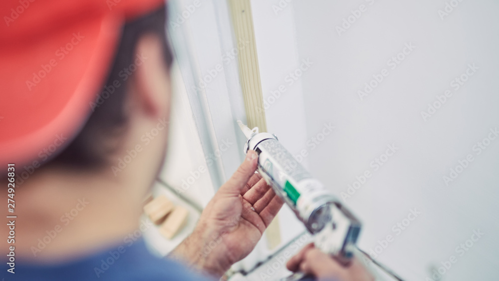 Worker using silicone for walls and door frame inside the house - renovation fixes. Worker using silicone for walls and door frame inside the house - renovation fixes.