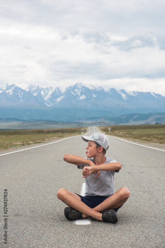 Young boy sitting on the beauty road in mountain