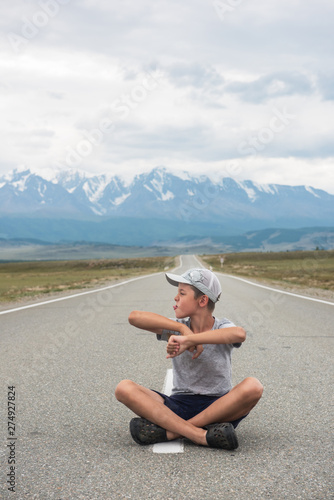 Young boy sitting on the beauty road in mountain