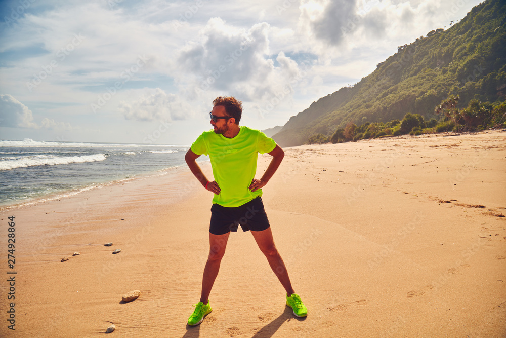 Sportsman stretching on a tropical sandy beach. Sportsman stretching on a tropical sandy beach.