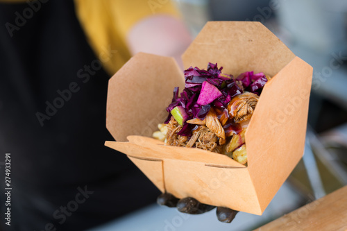 Man serving a chicken kebab with chips in a box at a Street food festival photo