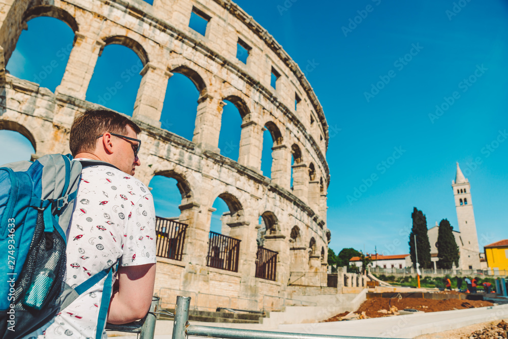 young man tourist standing near old roman coliseum in pula croatia. tourism concept