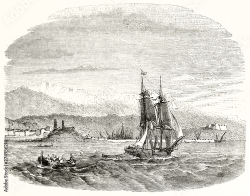 Ancient sailboat crossing the French sea with Antibe city and mountains on background. Ancient grayscale etching with fading borders. By Montigneul publ. on Magasin Pittoresque Paris 1848 photo