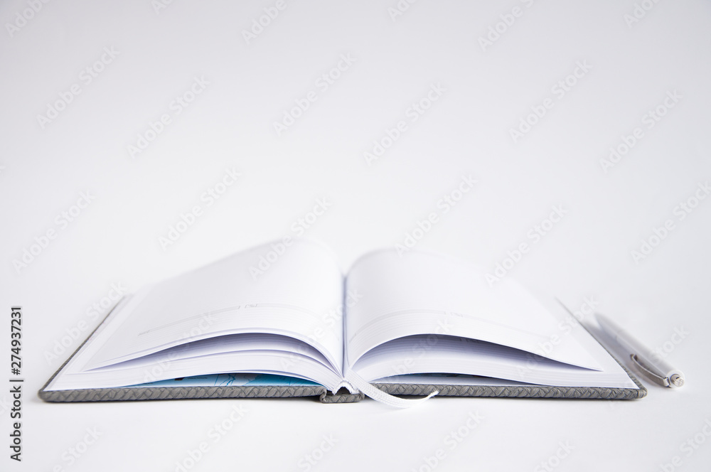 open notebook on the table. On the notebook is a pen or marker. On a white background open notebook on the table. On the notebook is a pen or marker. On a white background
