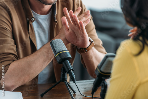 cropped view of radio host showing no sign while recording podcast with colleague