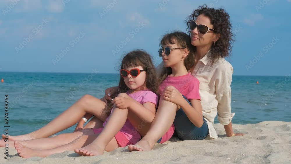 Family on vacation. Cute little girls with their mother are sitting on the sand on the seashore. Family on vacation. Cute little girls with their mother are sitting on the sand on the seashore.