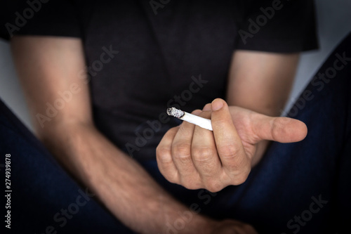 Man holding a cigarette, closeup cigarette and hand. Bad habits.