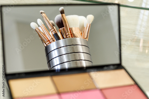 makeup brushes are reflected in a palette mirror with shadows photo