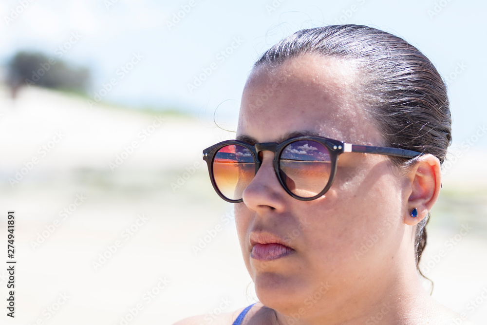 close up on face of woman wearing sunglasses on the beach close up on face of woman wearing sunglasses on the beach