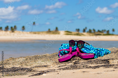 sandals, sunglasses and beach dress on the sand, background beach of Aguas Belas, Ceará - Brazil © CESARVR