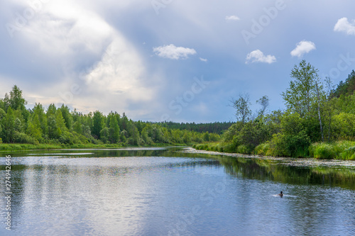 Picturesque summer landscape with northern river and forest in summer cloudy day. Travelling and discovering distant places of Earth. View from floating boat. Chernaya river, Karelia, Russia