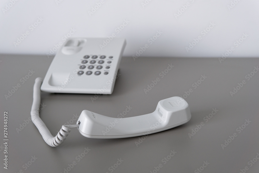 Modern white landline office phone with a hook. Technical support concept. No answer. Closeup white phone , office phone on the desk. Closeup white phone , office phone on the desk. Modern white landline office phone with a hook. Technical support concept. No answer. Closeup white phone , office phone on the desk. Closeup white phone , office phone on the desk.
