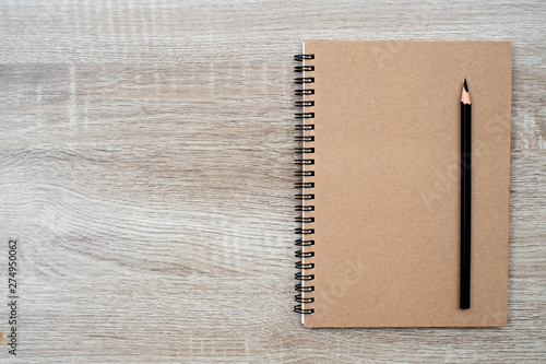 Top view, blank book and pencil on blank book on the wooden table.