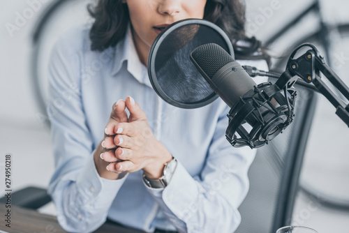 cropped shot of radio host speaking in microphone in broadcasitng studio