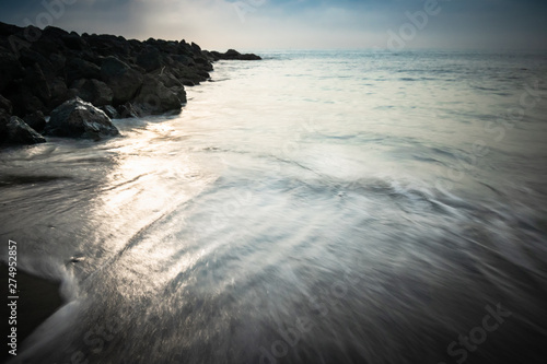 beautiful sandy scenic beach in sunset  with rocky breakwater in long exposure in basque country  france  creative background