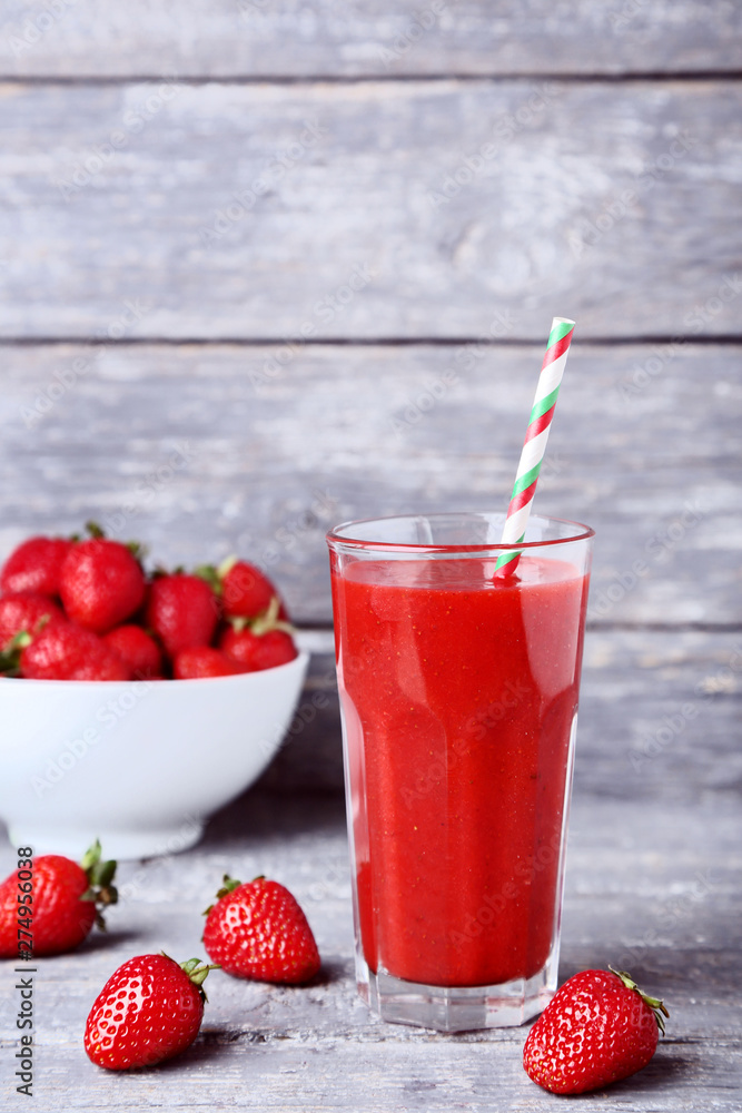 Smoothie in glass with strawberries on grey wooden table Smoothie in glass with strawberries on grey wooden table