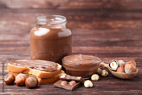Bread with melted chocolate and hazelnuts on brown wooden table