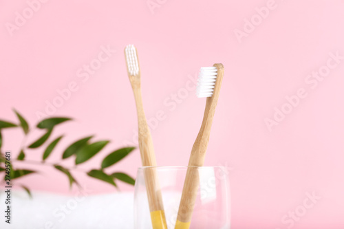 Bamboo toothbrushes in glass on pink background