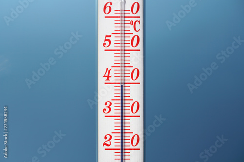 Thermometer during hot weather with sky in background