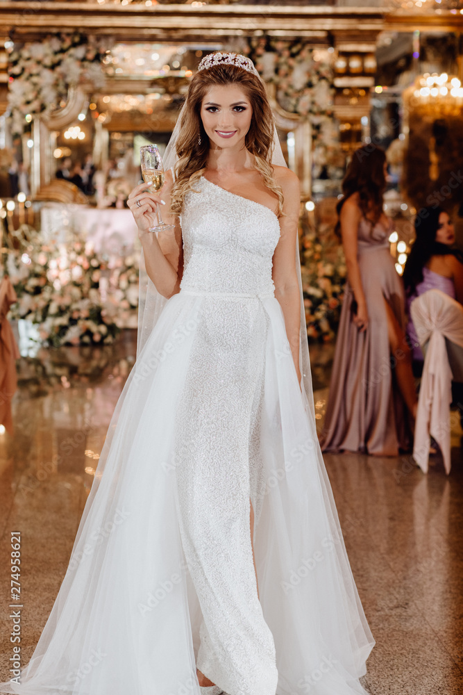 Sharming Character Bride with Glass of Champagne. Portrait of Beautiful Happy Smiling Woman in Wedding Dress with Long Hair Luxury Delight Celebratory Make-up Standing in Ceremony Room