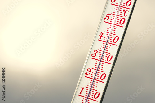 Thermometer during hot weather with sun in background